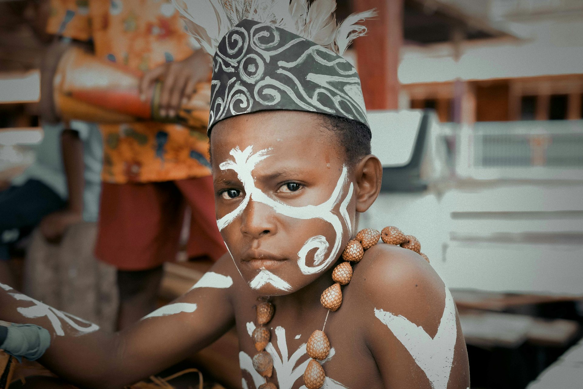 a young boy with a headdress and a necklace